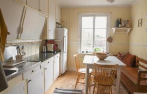 une cuisine avec des placards blancs et une table avec des chaises dans l'établissement Amazing Home In Stjrnhov With Kitchen, à Stjärnhov