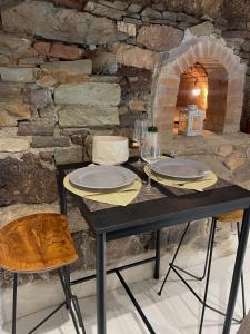 uma mesa com pratos e copos de vinho e uma parede de pedra em Ar Maen em Lanvollon