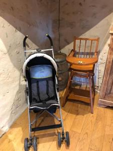 a baby stroller and a chair in a room at Maison superbe sur 2 étages avec piscine in Celles +30 photos