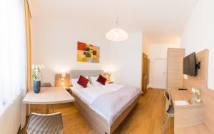 a bedroom with a bed and a table and a tv at Berghamer's Gasthof Hotel in Neukirchen am Walde