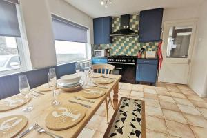 a kitchen with a table with plates and wine glasses at Sea-Views-3 Bed-Detached Bungalow-Secure Garden-Trearddur Bay in Trearddur