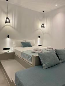 a white bedroom with two beds and two lights at Asteras Mini Suites in Naousa