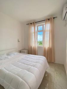 ein Schlafzimmer mit einem weißen Bett und einem Fenster in der Unterkunft 4 BR Blissful Breeze apartment in Albion