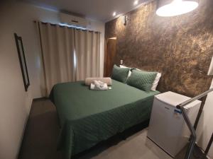Un dormitorio con una cama verde con un animal de peluche. en Vitória Suítes - Vila de São Jorge en Sao Jorge