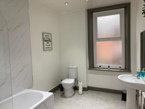 a bathroom with a toilet and a sink and a window at Rectory4 -Lovely 4 Bdrm 6 Beds Gateshead Free Parking in Gateshead