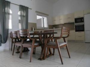 uma cozinha com uma mesa de madeira e cadeiras em Beautiful villa five minutes from Coral Bay beach! em Coral Bay