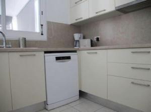 uma cozinha com armários brancos e um lavatório em Beautiful villa five minutes from Coral Bay beach! em Coral Bay