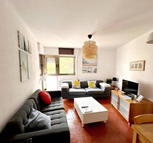 a living room with a couch and a tv at Apartamento Playa Merón in San Vicente de la Barquera +6 photos