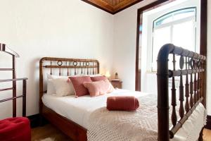 a bedroom with a bed with white sheets and pink pillows at Casa da Luz - Country House with Terrace in Semide