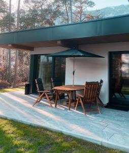 een tafel met stoelen en een parasol op een patio bij Residenz Bergzauber in Ötztal-Bahnhof