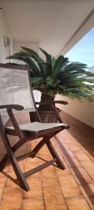 a wooden chair sitting on a balcony with a palm tree at EL RINCÓN DEL GUADALQUIVIR in La Rinconada