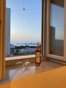 a bottle of whiskey and glasses sitting on a window sill at Asteras Mini Suites in Naousa