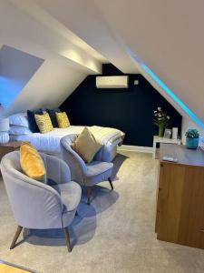 a attic room with a bed and two chairs at Stunning studio flat with own large garden in Shrewsbury SLEEPS 2 in Shrewsbury