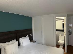 a bedroom with a white bed and a toilet at Kyriad Epernay in Épernay