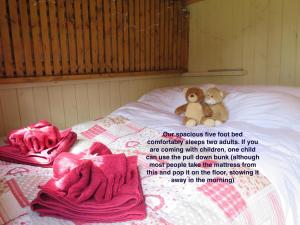 two teddy bears sitting on a bed with pink towels at Fernwood in Ringwood