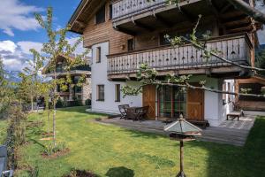 ein Haus mit einer Veranda und einem Garten mit einem Hof in der Unterkunft Steinberghaus Apartments in Leogang