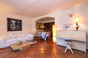 uma sala de estar com um sofá branco e um piano em L’aldiola - Happy Rentals em Porto Rotondo