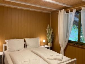 a bedroom with a white bed with a window at Kantor See-Chalets am Millstätter See in Rothenthurn