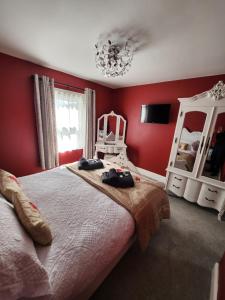 um quarto com uma cama grande e paredes vermelhas em East Dart Inn em Yelverton