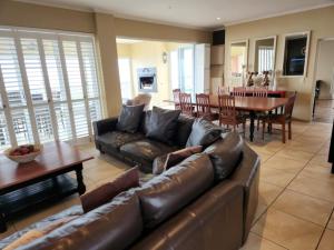 a living room with a leather couch and a table at Villa Penthouse 17-5 in Mossel Bay