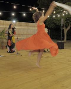 una mujer con un vestido naranja bailando en una pista de baile en Baia di Gallipoli Camping Village, en Gallipoli