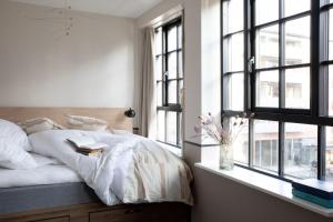 Schlafzimmer mit einem Bett mit weißer Bettwäsche und Fenstern in der Unterkunft Bob W Østerbro Copenhagen in Kopenhagen