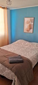 uma cama num quarto com uma parede azul em Excelente departamento cerca del Movistar Arena em Santiago