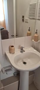 a white bathroom with a sink and a mirror at Excelente departamento cerca del Movistar Arena in Santiago