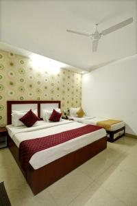 Hotel Claytone Near Delhi Airport في نيودلهي: غرفة نوم بسرير كبير ومخدات حمراء وبيضاء