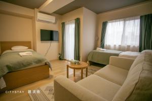 une chambre d'hôtel avec deux lits et un canapé dans l'établissement CityStay難波南, à Osaka