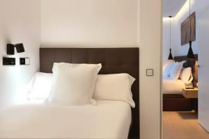 Woohoo Rooms Boutique Luna في مدريد: غرفة نوم بسرير ابيض مع مخدات بيضاء