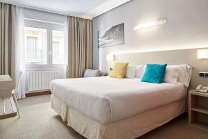 a hotel room with a large white bed with blue pillows at Hotel Parma in San Sebastián