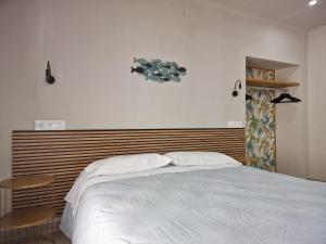 a bedroom with a white bed with a wooden headboard at Pensió i Apartament Torrent in L'Escala