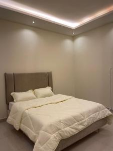 شقه غرفتين نوم وصاله ومجلس ومطبخ في الرياض: غرفة نوم بسرير ذو شراشف ووسائد بيضاء