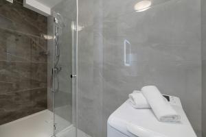 a bathroom with a shower and a toilet with towels at Międzywodzie Beautiful Apartment with Garden & Parking by Renters in Międzywodzie