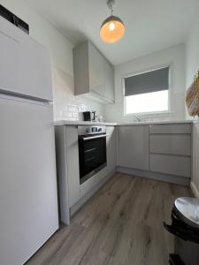 a kitchen with white cabinets and a stove and a refrigerator at Chalet 319, Hemsby - Two bed chalet, sleeps 5, pet friendly, bed linen and towels included in Hemsby