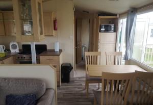 a kitchen and dining room with a table and chairs at 6 Berth Caravan With Decking At Naze Marine Holiday Park Ref 17071p in Walton-on-the-Naze