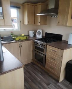 a kitchen with wooden cabinets and a stove top oven at 6 Berth Caravan With Decking At Naze Marine Holiday Park Ref 17071p in Walton-on-the-Naze