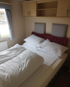 een groot wit bed met een rood hoofdeinde in een slaapkamer bij 6 Berth Caravan With Decking At Naze Marine Holiday Park Ref 17071p in Walton-on-the-Naze