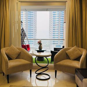 a living room with two chairs and a table and a large window at High Rise Executive Apartments Facing Centaurus Mall Islamabad in Islamabad