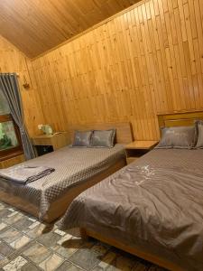 two beds in a room with wooden walls at Mộc House in Kon Tum Kơ Pang