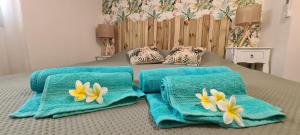 Una cama con toallas azules y flores. en Charmant T2 à 50m du lagon en Étang-Salé les Bains