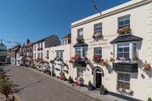 a row of white buildings on a street with flowers at The Kings Head in Deal