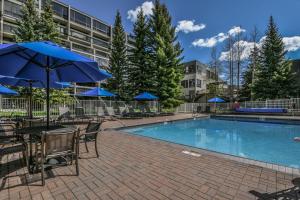 a pool with tables and chairs and blue umbrellas at Lakeside 1497 in Keystone