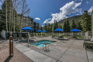 a pool with chairs and blue umbrellas on a patio at Lakeside 1497 in Keystone
