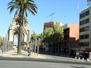 an empty city street with palm trees and buildings at Hotel Arizona in Mexico City