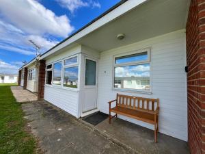 a bench sits outside of a house at Chalet 319, Hemsby - Two bed chalet, sleeps 5, pet friendly, bed linen and towels included in Hemsby