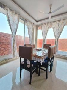 Lavish 3BHK Villa F2 - Private Pool - The Heaven في Pālghar: غرفة طعام مع طاولة وكراسي ونوافذ