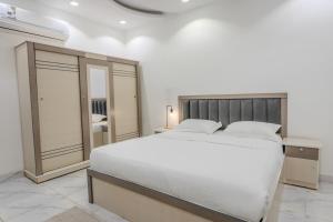 um quarto com uma grande cama branca e um espelho em Luxurious Family 3 Bedroom Apartments 10 Mins Drive to Al-Masjid Nabawi - Qaswarah residence em Al Madinah