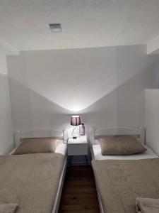 a room with two beds and a table with a lamp at Lena 2 in Jajce